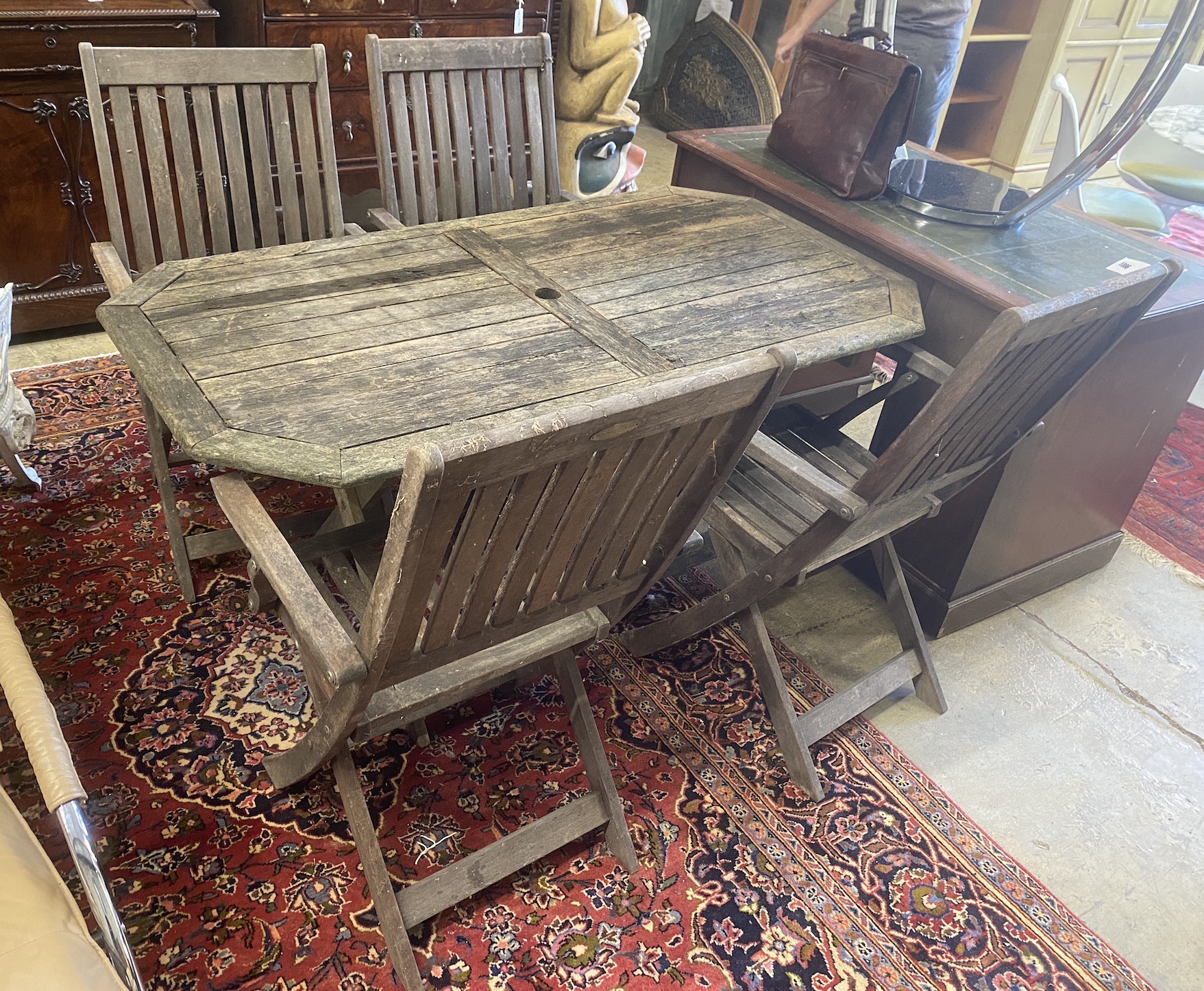 A weathered teak folding garden table, width 150cm, depth 80cm, height 70cm together with four folding teak elbow chairs